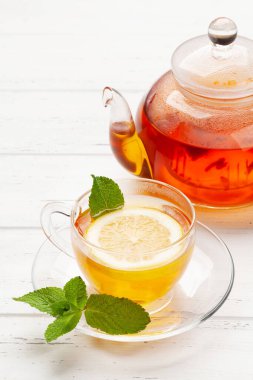 Nane ve limonlu bitki çayı. Tahta masada çay fincanı ve çaydanlık.