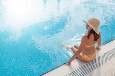 Yaz tatilinde yüzme havuzunda dinlenen bir kadın. Fotokopi alanı ile sıcak güneşli tatil kavramı