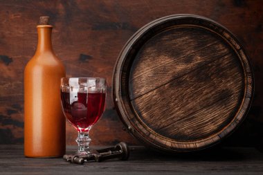 Şarap şişesi, bir kadeh kırmızı şarap ve eski ahşap fıçı. Kopyalama alanı ile