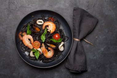 Deniz ürünleri, domates ve fesleğenli siyah spagetti makarna. Üst görünüm düzlüğü