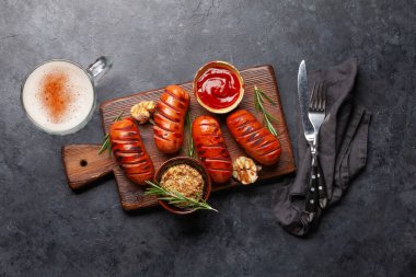 Ahşap tahtada sıcak ızgara sosis, ketçap ve hardal. Üst görünüm düzlüğü