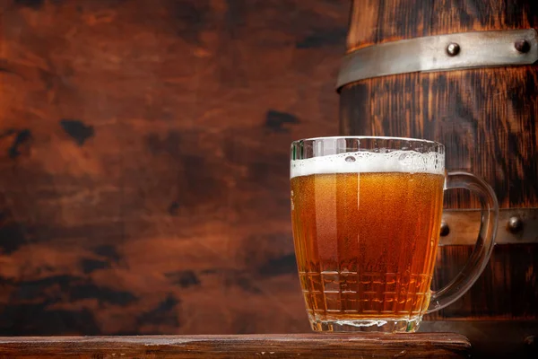 Mug of light lager beer and old wooden barrel. With copy space