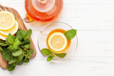 Nane ve limonlu bitki çayı. Çay fincanı ve çaydanlık ahşap masada. Üst görünüm düzlüğü kopyalama alanı ile yatıyordu