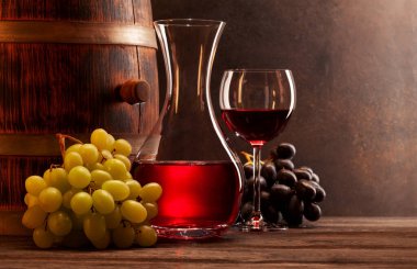 Şarap sürahisi, bir bardak kırmızı şarap ve eski ahşap fıçı. Kopyalama alanı ile