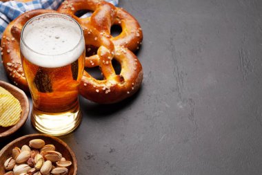 Bira bardağı, fındık, patates cipsi ve taş masada deniz tuzu ve taze pişmiş kraker. Klasik bira atıştırmalığı. Kopyalama alanı ile