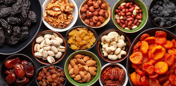 Various dried fruits and nuts on a dark stone table. Top view flat lay