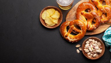 Bira bardağı, fındık, patates cipsi ve taş masada deniz tuzu ve taze pişmiş kraker. Klasik bira atıştırmalığı. Üst görünüm düzlüğü kopyalama alanı ile yatıyordu