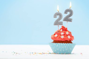 Doğum günü pastası. 22 numara. Mavi arka planda yanan mum ve selamlarınız için fotokopi alanı.