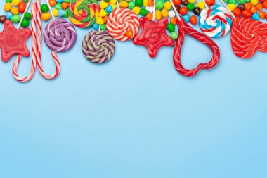 Çeşitli tatlı çeşitleri var. Şeker, bonbon ve mavi arka plan. Üst görünüm düzlüğü kopyalama alanı ile yatıyordu