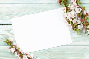 Ahşap arka planda kiraz çiçeği açgözlülüğü kartı. Kutlama kartı ya da yemek menüsü için sakura dalı ile bahar arkaplanı. Üst görünüm düzlüğü kopyalama alanı ile yatıyordu