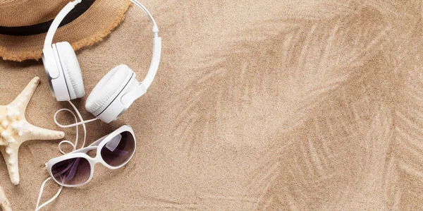 Travel vacation and music concept with headphones, sunglasses and starfish on sand backdrop. Top view with copy space. Flat lay