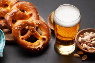 Bira bardağı, fındık, patates cipsi ve taş masada deniz tuzu ve taze pişmiş kraker. Klasik bira atıştırmalığı.