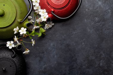 Çay demliğinde Japon çayı ve taş masada kiraz çiçeği. Üst görünüm düzlüğü kopyalama alanı ile yatıyordu