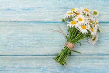 Mavi ahşap masada papatya çiçeği buketi. Üst görünüm düzlüğü kopyalama alanı ile yatıyordu