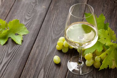 Beyaz şarap kadehi ve üzüm eski ahşap masada.