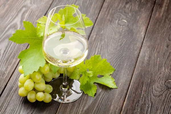 Beyaz şarap kadehi ve üzüm, fotokopi alanı olan eski ahşap masada.