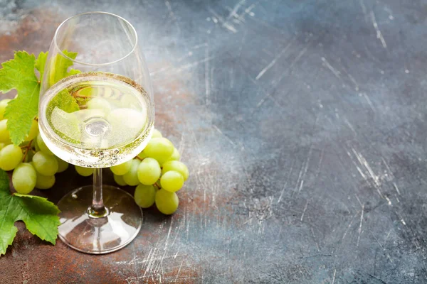 Beyaz şarap kadehi ve üzüm, fotokopi alanı olan eski taş masanın üzerinde.