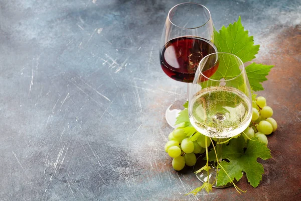Beyaz ve kırmızı şarap kadehleri ve üzümler fotokopi alanı olan eski taş masada.