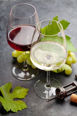 Beyaz ve kırmızı şarap kadehleri ve eski taş masanın üzerinde eski model tirbuşon.