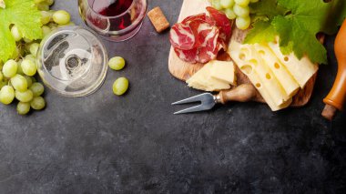 Beyaz ve kırmızı şarap bardakları, peynir ve jambonlu aperatif tabağı. Kopyalama alanı olan. Üst görünüm düzlüğü