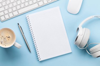 Ofis masasında malzemeler, kahve ve mavi üzerine boş not defteri. Yaratıcılık ve ilham çalışması konsepti. Üst görünüm düzlüğü kopyalama alanı ile yatıyordu