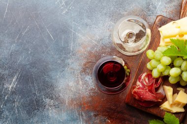 Beyaz ve kırmızı şarap bardakları, peynir ve jambonlu aperatif tabağı. Kopyalama alanı olan. Üst görünüm düzlüğü