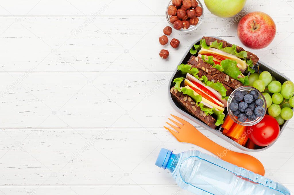 Healthy school lunch box with sandwich and fresh vegetables, water bottle, nuts and fruits. Top view flat lay with copy space