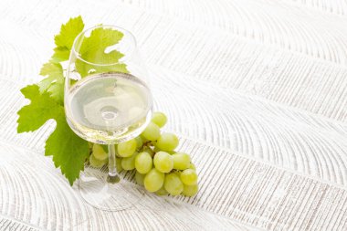 Beyaz şarap kadehi ve üzüm, fotokopi alanı olan eski ahşap masada.