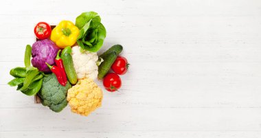 Tahta masadaki kutuda çeşitli taze sebzeler. Domates ve salatalık Üst görünümü düz ve kopyalama alanı var