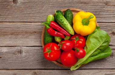 Tahta masada çeşitli taze sebzeler. Domates, biber ve salatalık. Üst görünüm düzlüğü kopyalama alanı ile yatıyordu