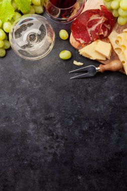 Beyaz ve kırmızı şarap bardakları, peynir ve jambonlu aperatif tabağı. Kopyalama alanı olan. Üst görünüm düzlüğü