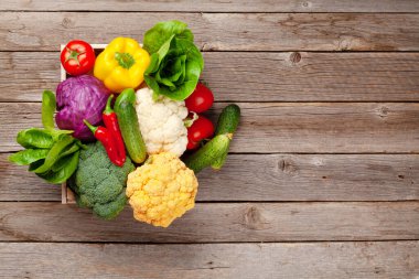 Tahta masadaki kutuda çeşitli taze sebzeler. Domates ve salatalık Üst görünümü düz ve kopyalama alanı var