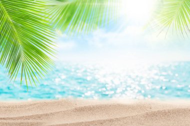Parlak dalgaları, palmiye yaprakları, kumsal ve güneşli mavi gökyüzü olan yaz denizi. Bulanık seyahat ve tatil arkaplanı