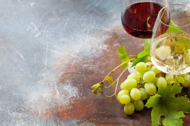 Beyaz ve kırmızı şarap kadehleri ve üzümler fotokopi alanı olan eski taş masada.