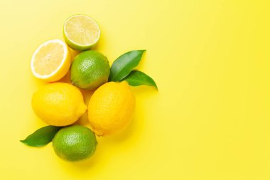 Sarı arka planda taze taze narenciye meyveleri. Limon ve limon. Üst görünüm düzlüğü kopyalama alanı ile yatıyordu