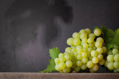 Tahta masada yaprakları olan beyaz üzüm. Kopyalama alanı ile