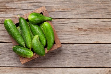 Tahta masadaki kutuda taze salatalık sebzeleri. Üst görünüm düzlüğü kopyalama alanı ile yatıyordu