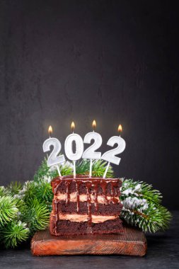 İçinde 2022 numara yanan mumlar ve köknar ağacı olan Noel pastası. Xmas selamlamalarınız için kopya alanı ile