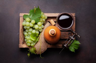 Kırmızı şarap kadehi, şişe ve tahta kutuda beyaz üzüm. Üst görünüm düzlüğü