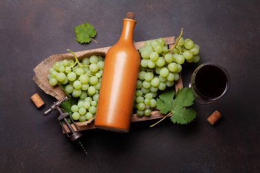 Kırmızı şarap kadehi, şişe ve tahta kutuda beyaz üzüm. Üst görünüm düzlüğü