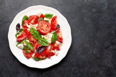 Taze domatesli Caprese salatası, fesleğen ve mozzarella peyniri. Üst görünüm düzlüğü kopyalama alanı ile yatıyordu