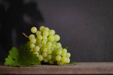 Tahta masada yaprakları olan beyaz üzüm. Kopyalama alanı ile