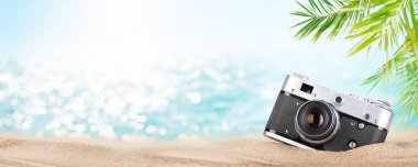 Tropikal sahilde palmiyeli ve parlak kumlu bir Retro kamera. Yaz tatili ve fotokopi alanı ile seyahat kavramı
