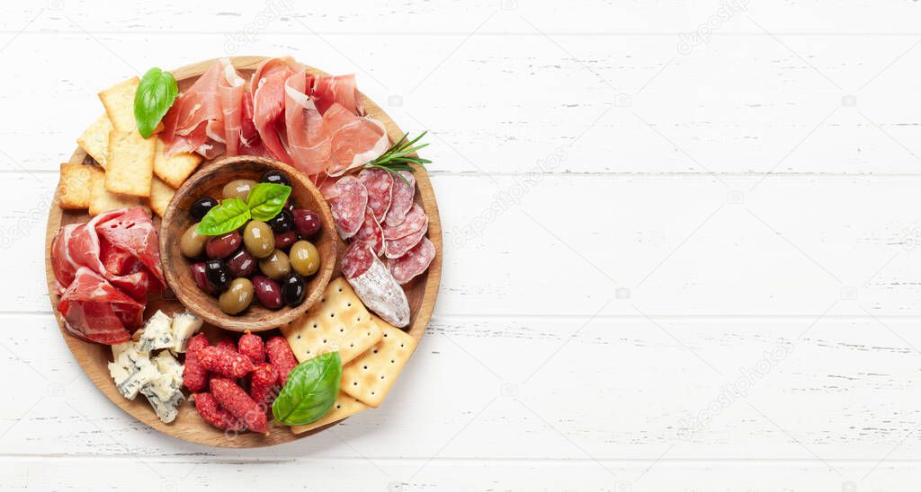 Antipasto board with prosciutto, salami, crackers, cheese and olives. Top view flat lay with copy space