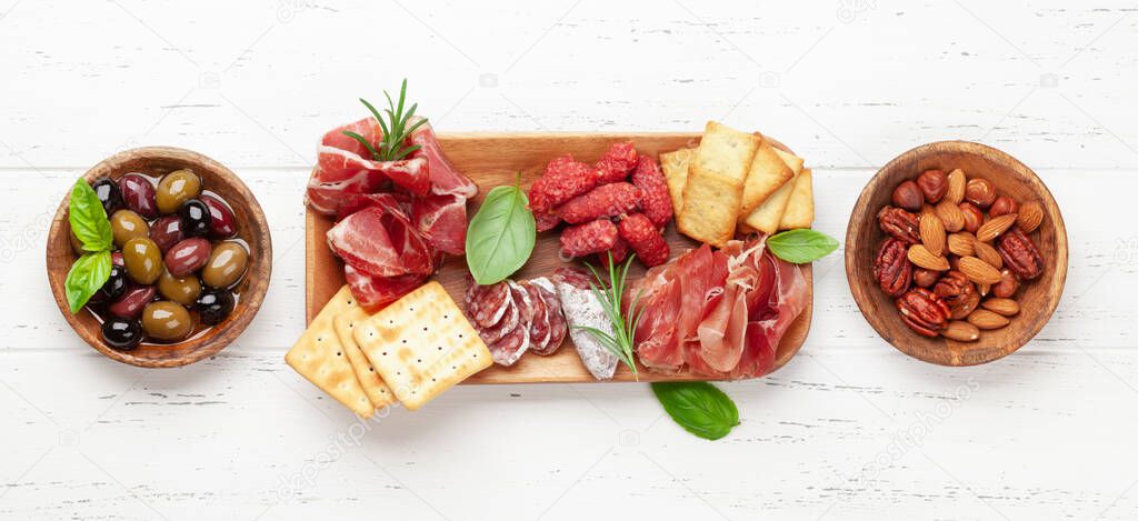Antipasto board with prosciutto, salami, crackers, cheese, nuts and olives. Top view flat lay