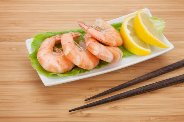 Cooked shrimps with lemon and chopsticks — Stock Photo, Image