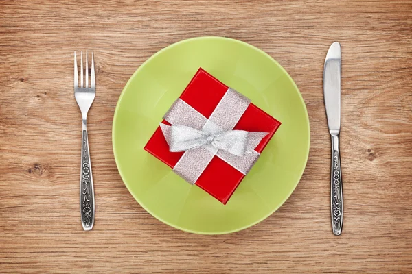 Gift box on plate and silverware — Stock Photo, Image