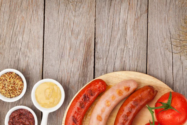 Grilled sausages with condiments and tomatoes — Stock Photo, Image