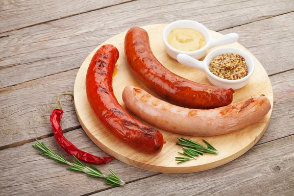 Various grilled sausages with condiments — Stock Photo, Image