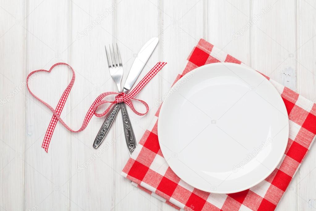 Empty plate, silverware and valentines day heart shaped ribbon